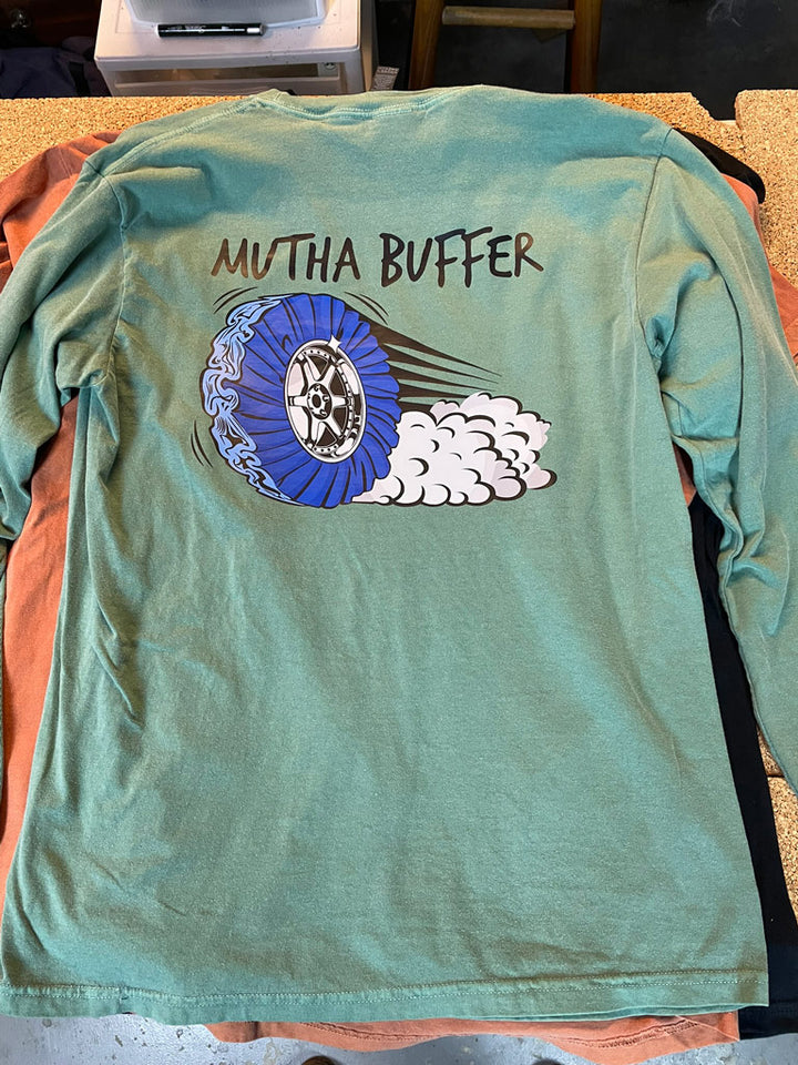 Seafoam green long-sleeve tee printed with “MUTHA BUFFER” text above a dynamic blue turbine buffer wheel graphic with motion streaks and billowing smoke.
