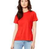 Woman wearing a Bella + Canvas Ladies' Relaxed Jersey Short-Sleeve T-Shirt in Red color, standing with a neutral expression and light blue jeans.