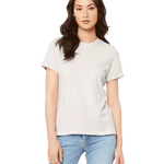 Woman wearing a Bella + Canvas Ladies' Relaxed Jersey Short-Sleeve T-Shirt in Vintage White color, standing with a neutral expression and light blue jeans.