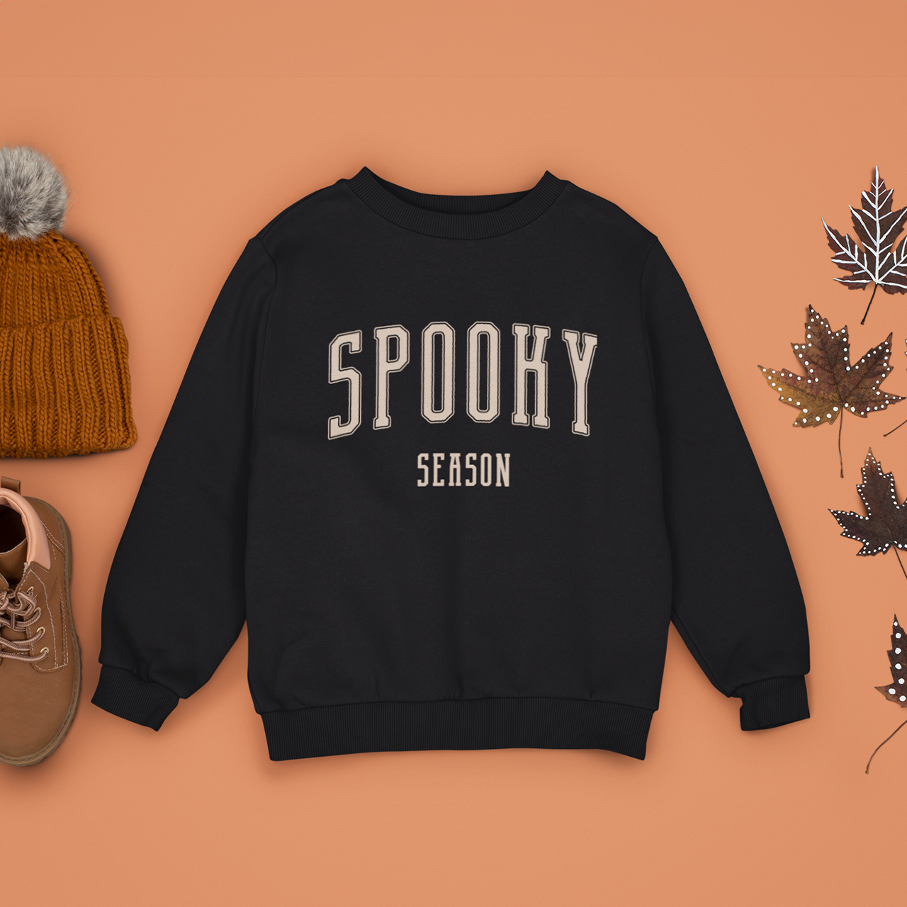 A black Crewneck Champion Power blend Sweatshirt, on an earthy autumn backdrop. This design features the words: Spooky Season, in an off white scholarly university font.