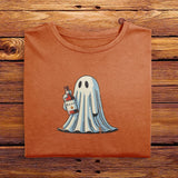 A folded vintage Comfort Colors Tshirt in Yam Orange color, laying on a wooden table. The retro design features a cute bedsheet ghost holding a bottle of liquor that says Boos.