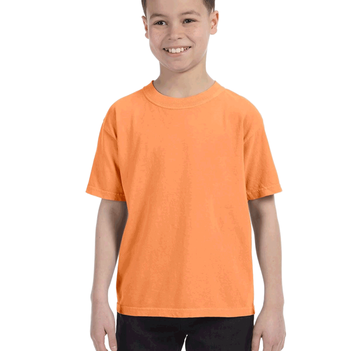 Young boy modeling a Comfort Colors Youth Midweight T-Shirt in "Melon" color, standing with a cheerful expression.