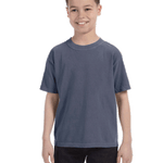 Child in a "Washed Denim" colored Comfort Colors Youth Midweight T-Shirt, smiling while standing with hands relaxed by his sides.