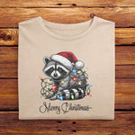 An Ivory White Comfort Colors Tshirt, with a vintage design featuring a cute raccoon wearing a Santa hat, wrapped in colorful Christmas lights. Merry Christmas is written below in a playful script font, perfect for holiday cheer.