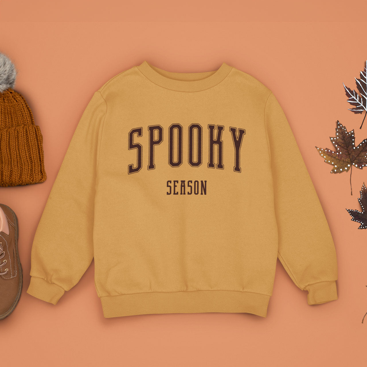 A Gold Glint Orange Crewneck Champion Power blend Sweatshirt, on an earthy autumn backdrop. This design features the words: Spooky Season, in an off white scholarly university font.