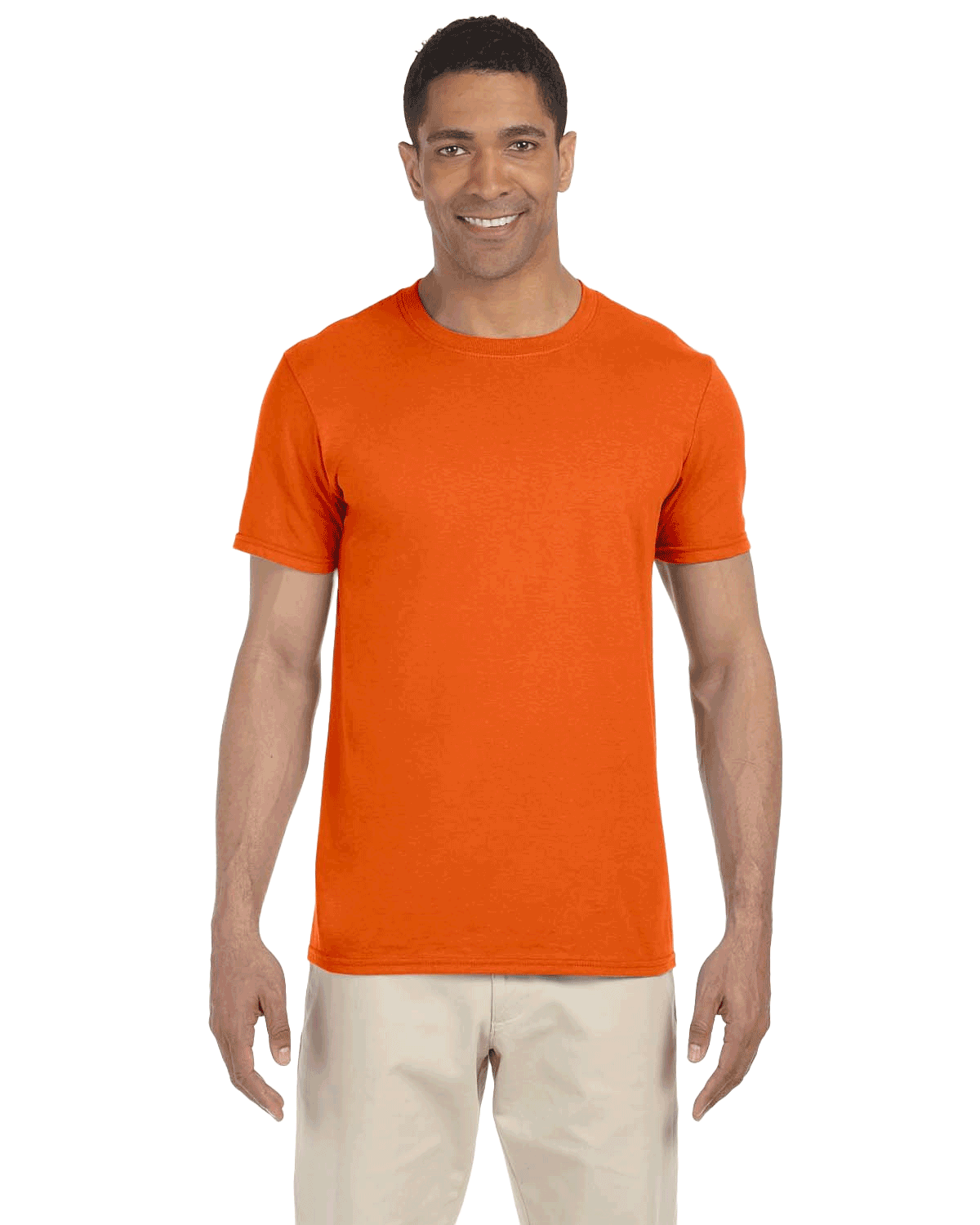 Man in a "Orange Sunset" colored Gildan SoftStyle T-shirt, standing with a relaxed posture and a friendly smile.