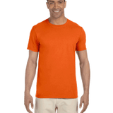 Man in a "Orange Sunset" colored Gildan SoftStyle T-shirt, standing with a relaxed posture and a friendly smile.