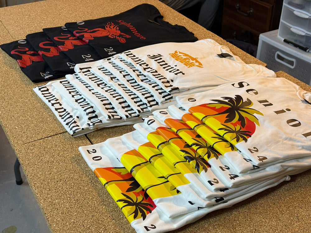 Print-MO tee stacks: black Salamonde tees with red salamander; cream Honor Society tees with gold crown; white Senior 2024 tees with sunset palm
