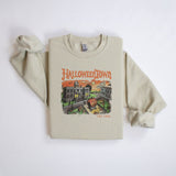 A vintage tan sweatshirt with a retro graphic print of a spooky town with a large pumpkin in front of a building. The text on the sweatshirt reads Halloweentown Est. 1998