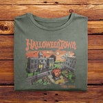 A vintage Comfort Colors Tshirt in Moss Green with a retro graphic print of a spooky town with a large pumpkin in front of a building. The text on the sweatshirt reads Halloweentown Est. 1998