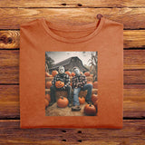 A Yam Orange folded Comfort Colors Tshirt, laying on a wooden table. The vintage design has Jason Vorhees from Friday the 13th, and Michael Meyers from Halloween, both in cozy flannels sitting together in a pumpkin patch. Jason is showing off his jack o lantern