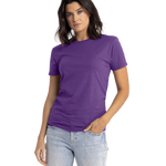 Next Level Apparel Unisex CVC Crewneck T-Shirt in "Purple Rush" color worn by a woman, standing casually with a neutral expression and one hand in her pocket.