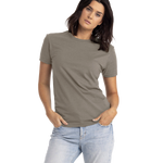 Next Level Apparel Unisex CVC Crewneck T-Shirt in "Warm Grey" color worn by a woman, standing casually with a neutral expression and hands in her pockets.