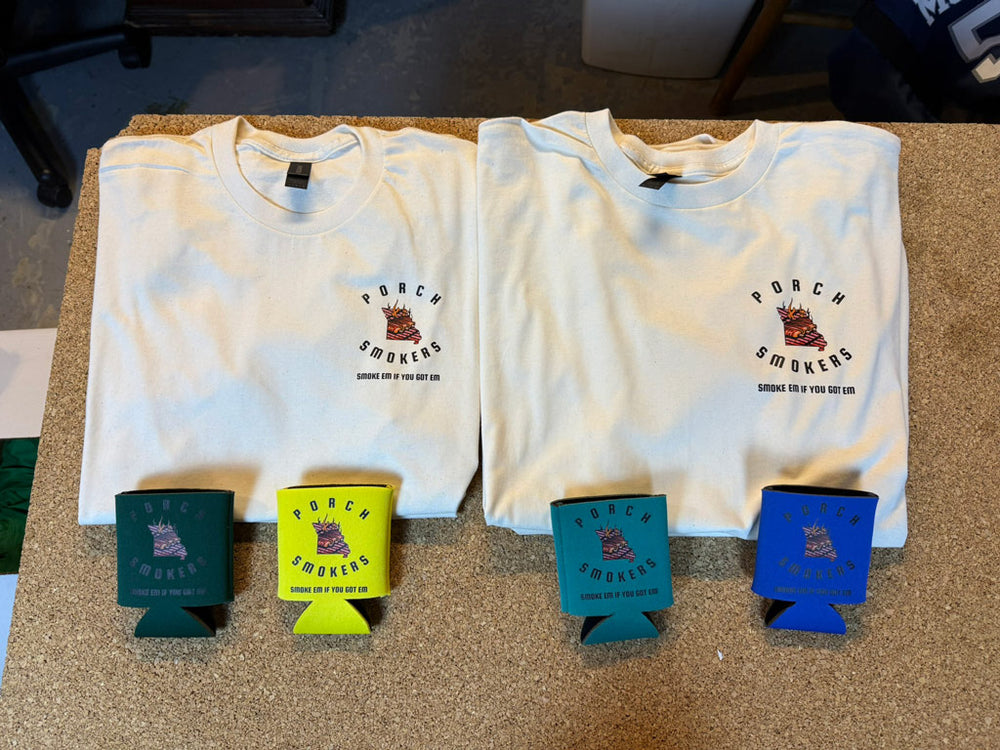 Two cream Porch Smokers t-shirts printed with Missouri grill map logo and ‘Smoke em if you got em’ slogan, paired with four branded can coolers.