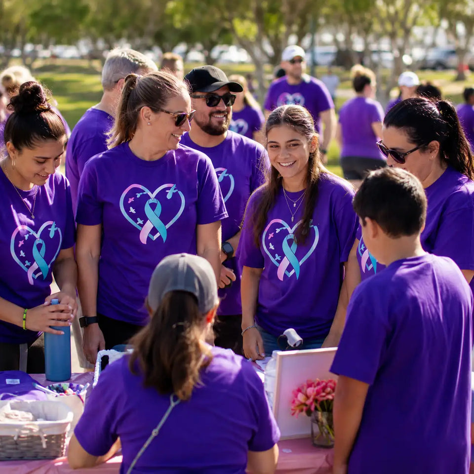 Community group wearing matching purple fundraiser shirts with an awareness ribbon design